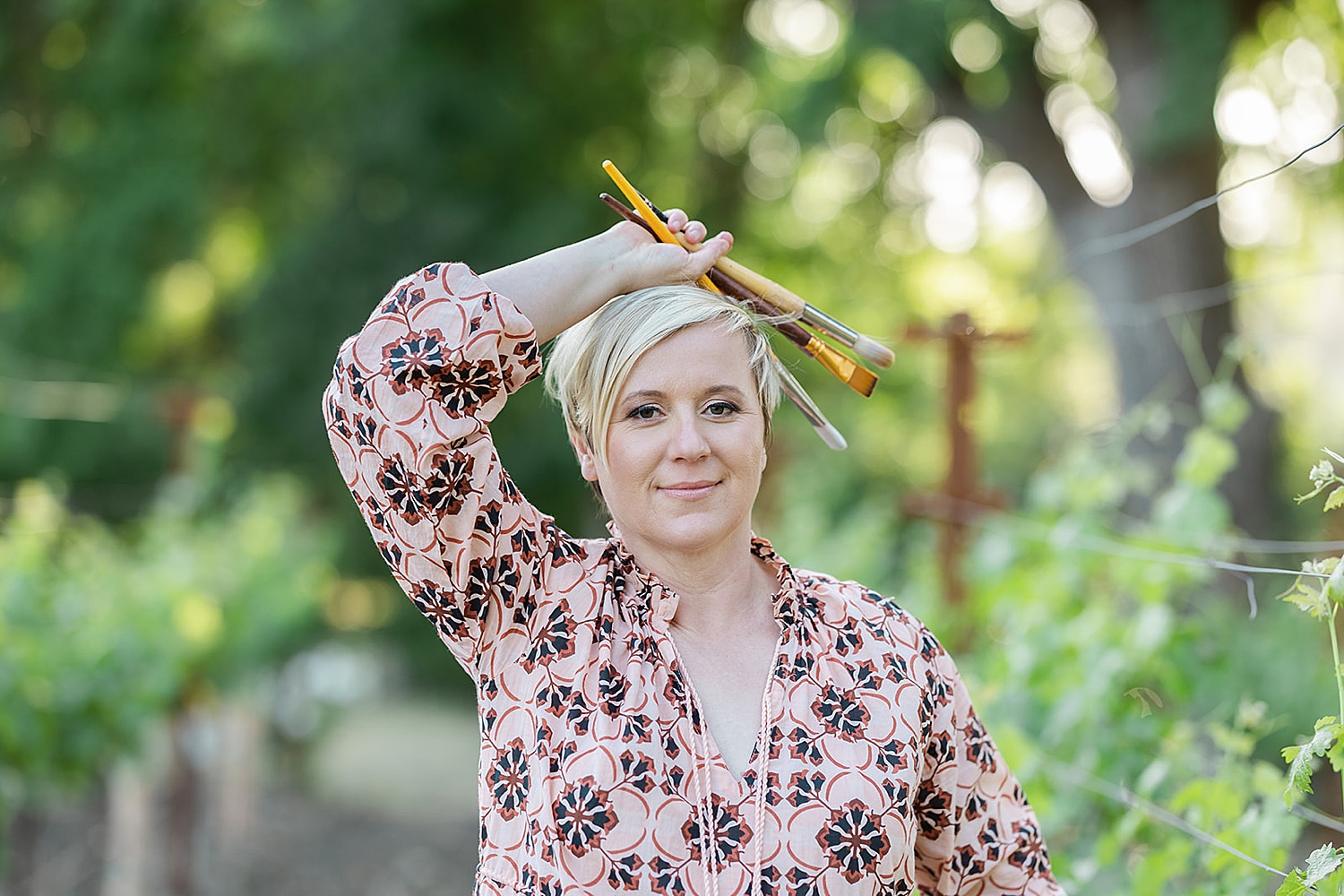 artist holding paint brushes over her head by Amy Thompson Photography