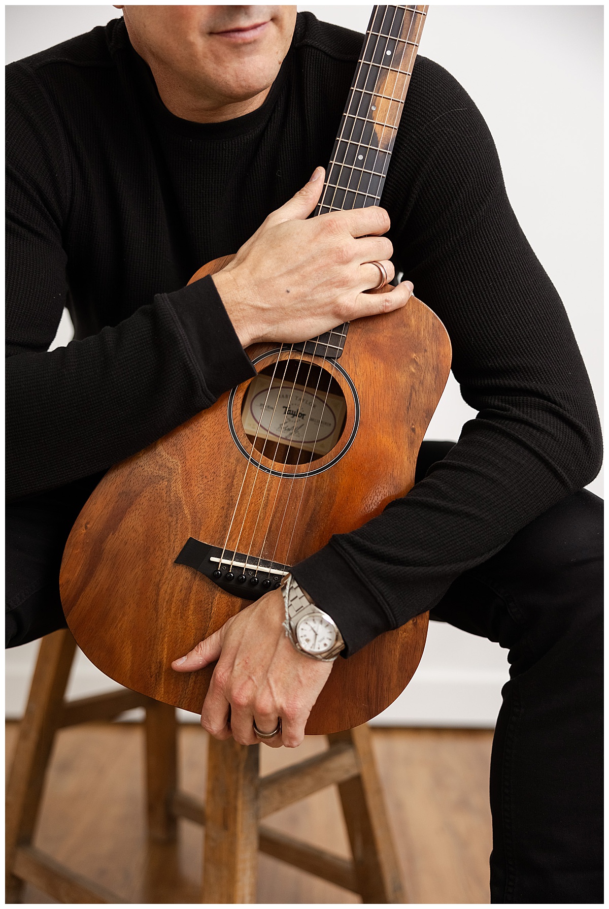 Adult grabs guitar while sitting on a chair as an example of Men’s Brand Photoshoot Ideas