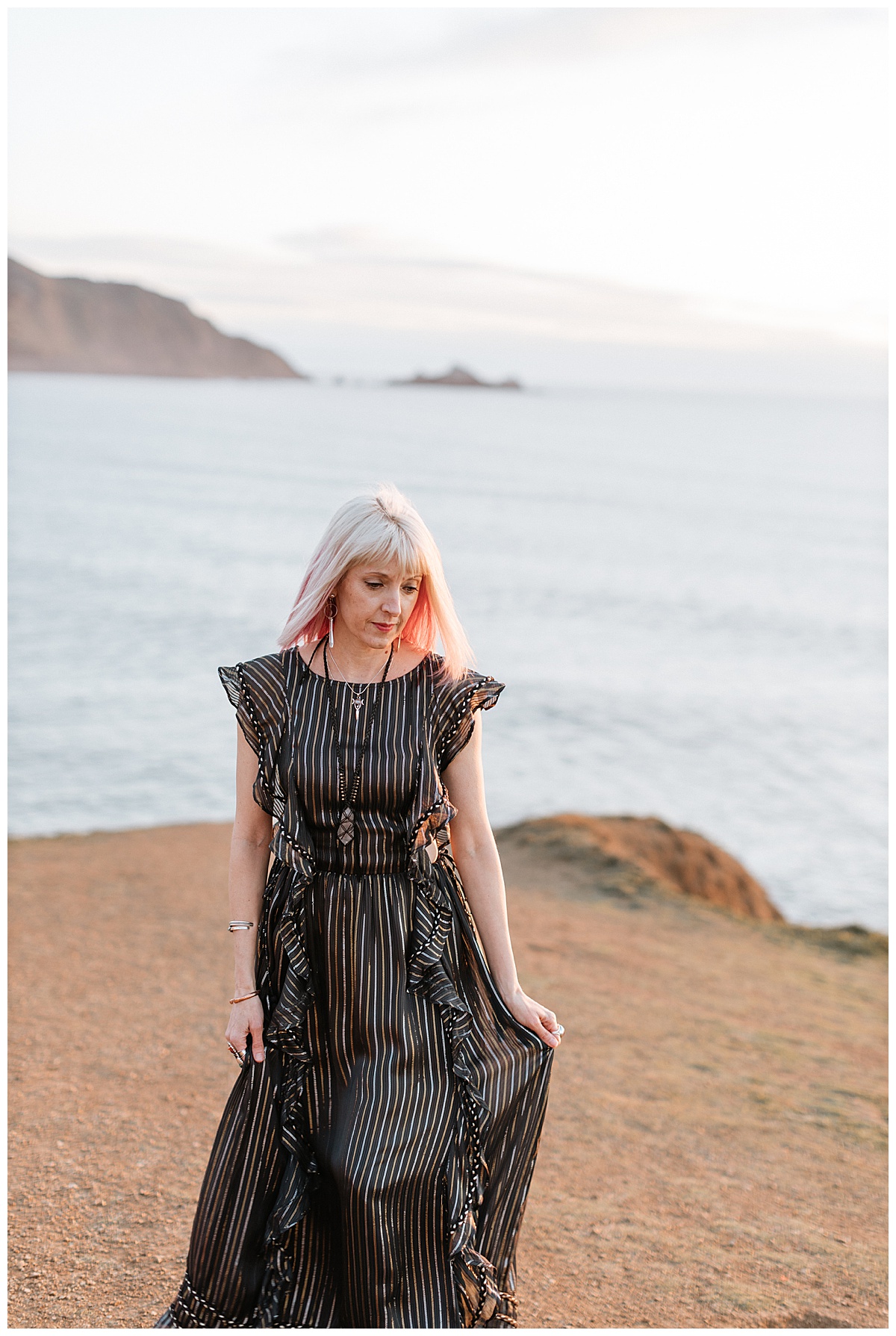 Woman holds her dress by the ocean for a Brand Photographer